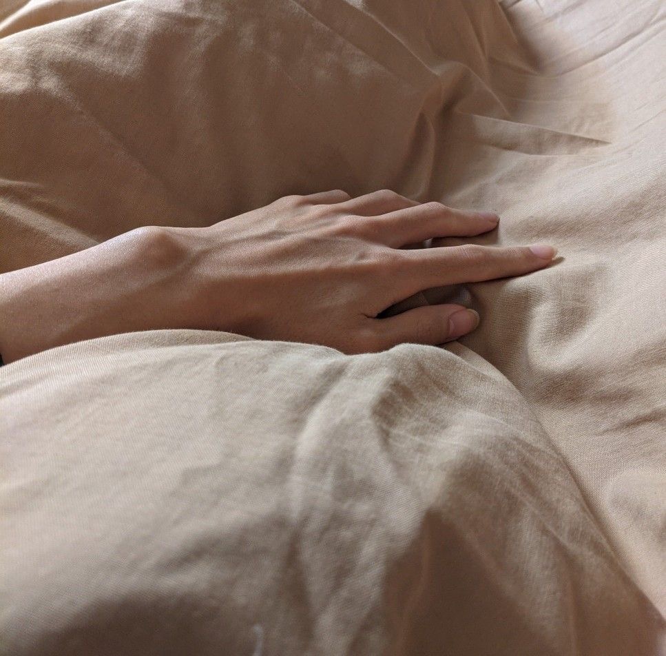 A quiet, restful moment — hand resting on soft linen